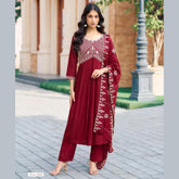 Woman wearing a red traditional outfit with white embroidery in an outdoor setting.