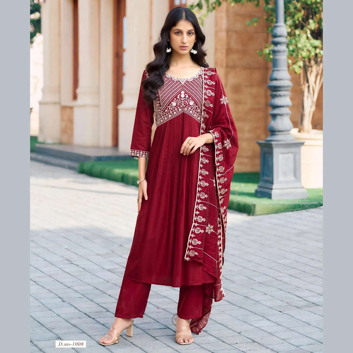 Woman wearing a red traditional outfit with white embroidery in an outdoor setting.